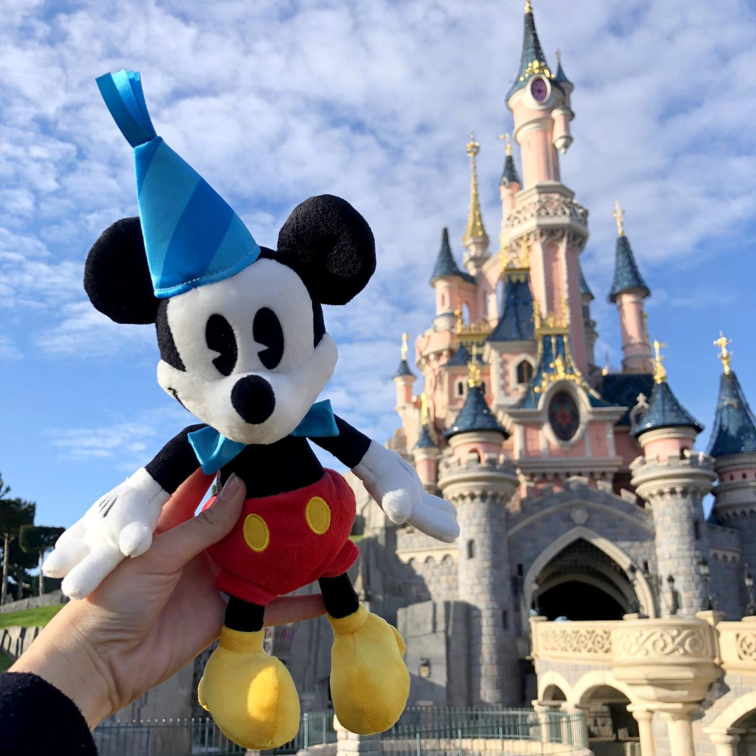 pupazzo di Mickey con cappellino festa di compleanno su sfondo con Castello
